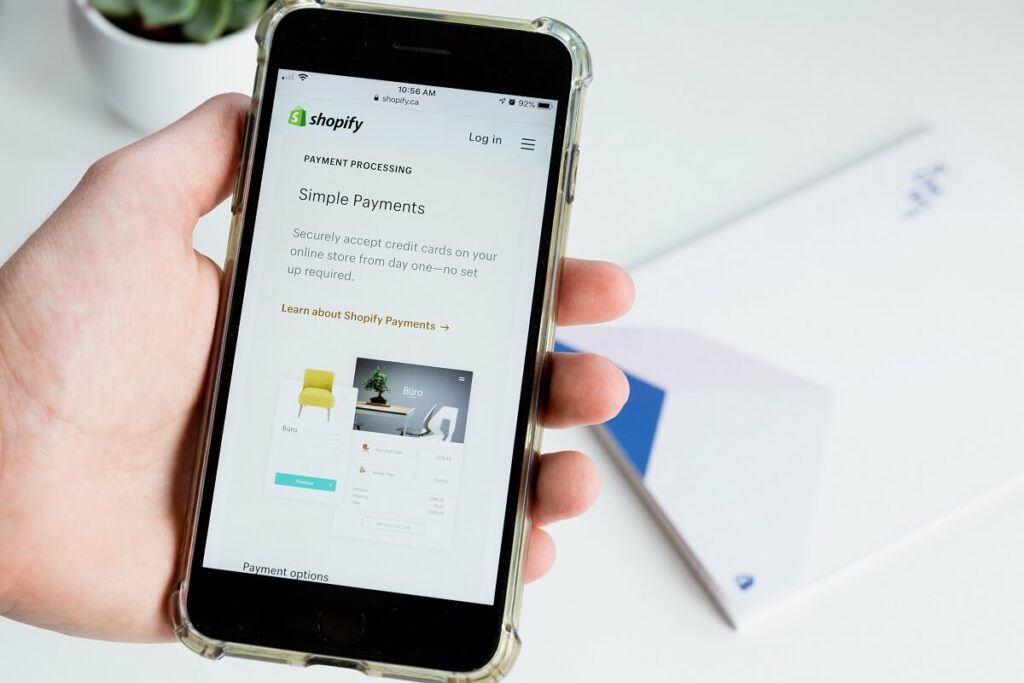 Close-up of a hand holding a mobile device with Shopify platform loaded
